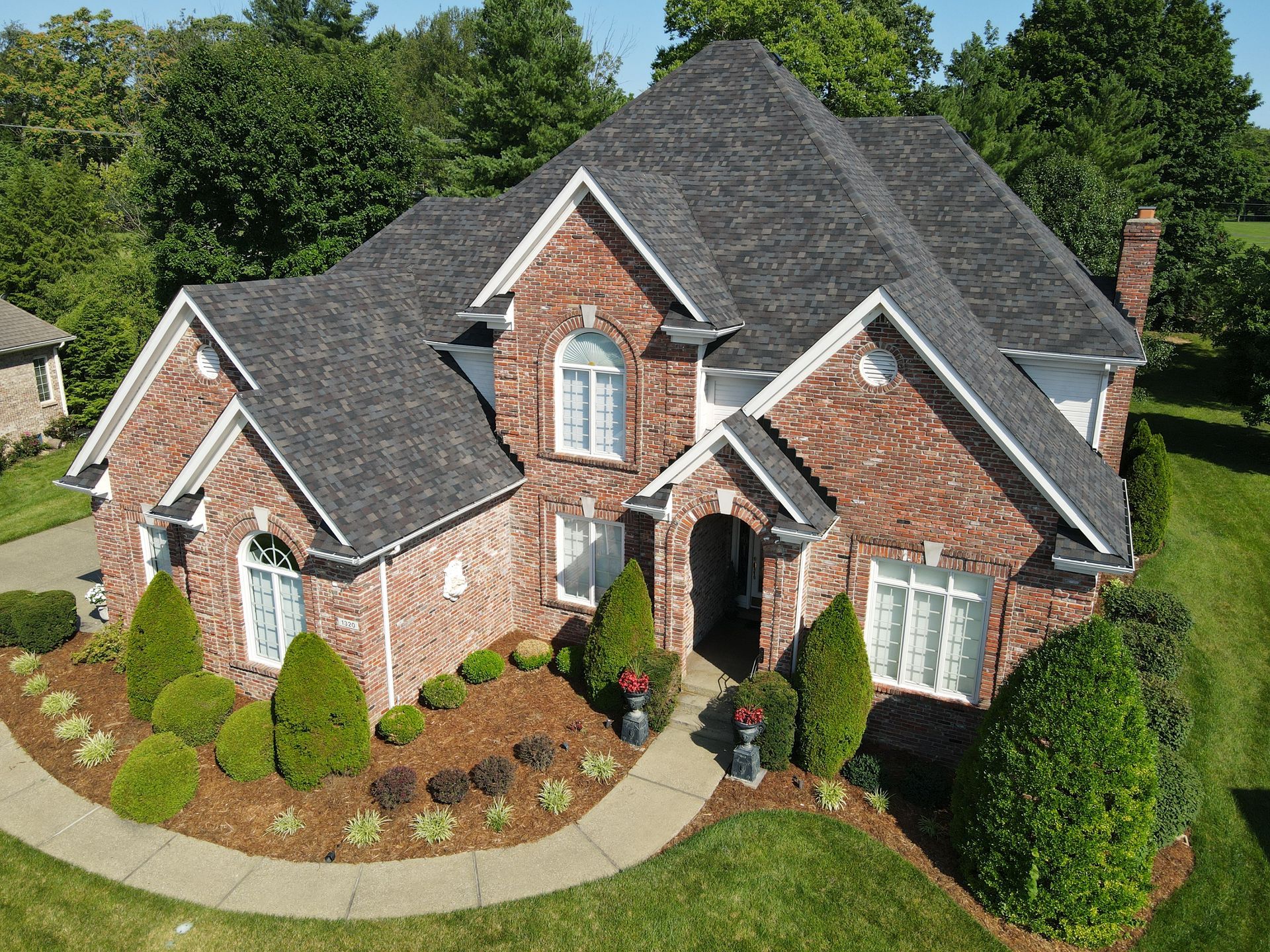 Brick house with dark gray roof and manicured landscaping.