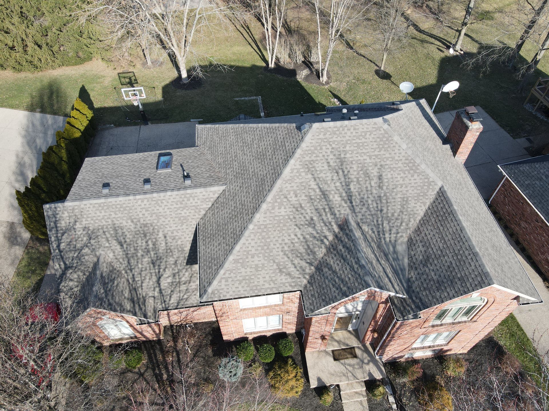 An aerial view of a large brick house with a gray roof.