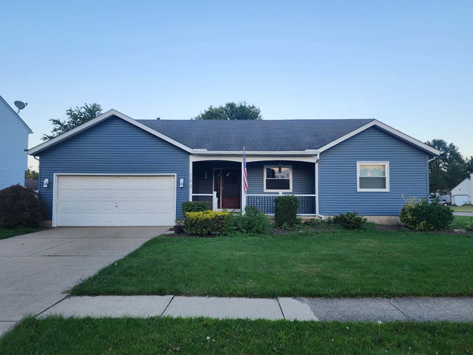 A blue house with a white garage door and a porch