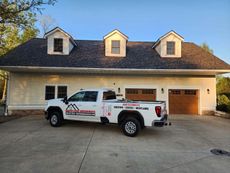 A white truck is parked in front of a large house.