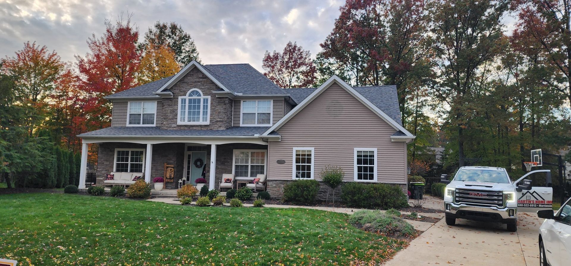 A house with a porch and chairs in front of it.