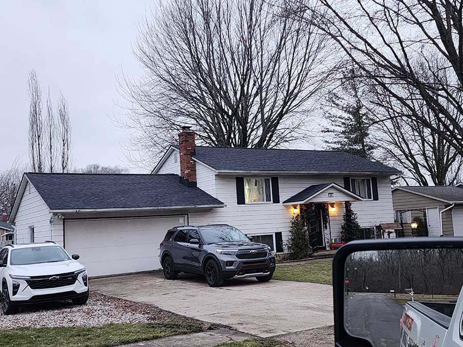 A white house with a black suv parked in front of it.