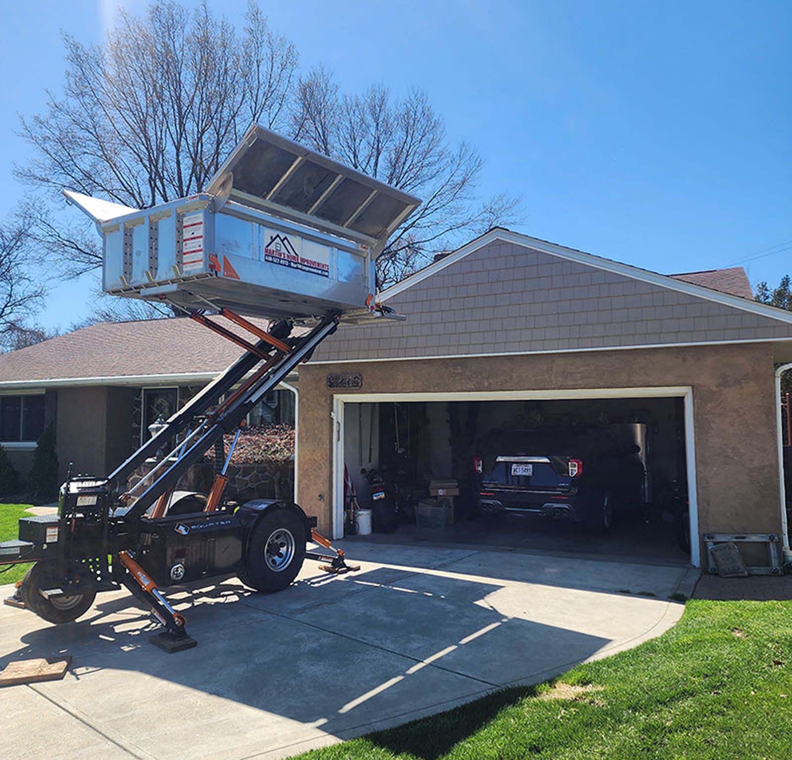 A dumpster on a trailer is parked in front of a house