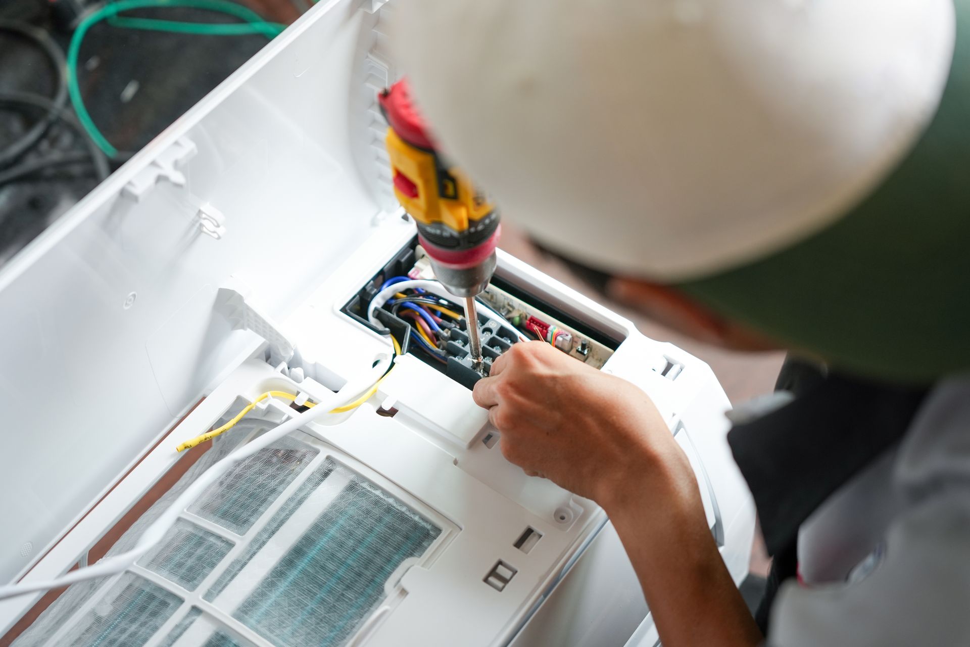 Person using a screwdriver to repair an air conditioner's internal components.