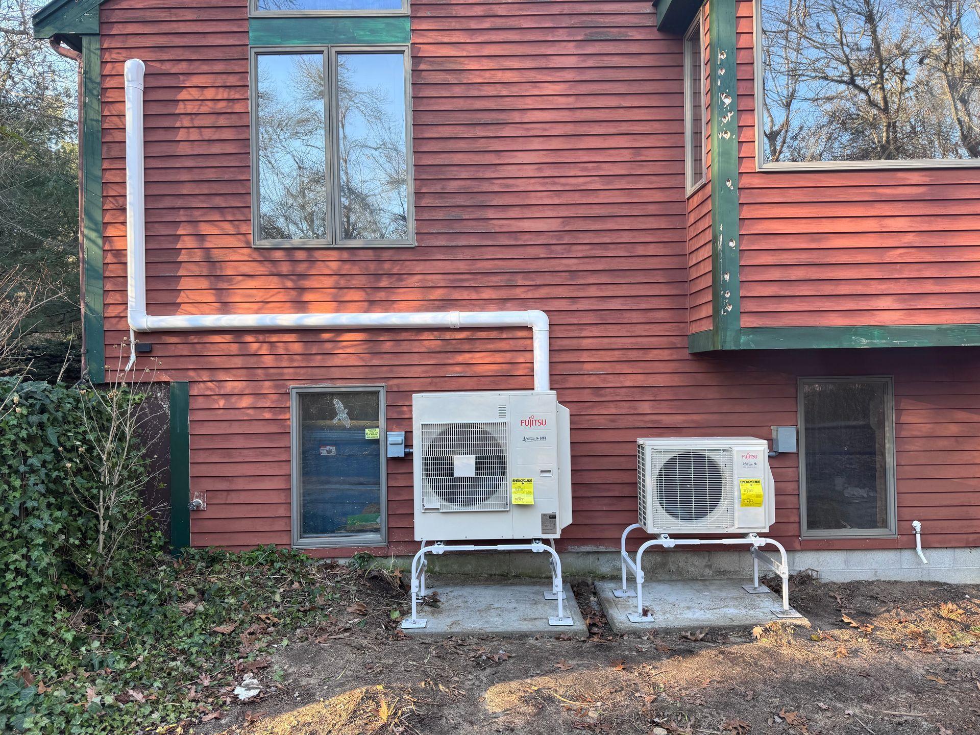 Two air conditioners are installed on the side of a house.