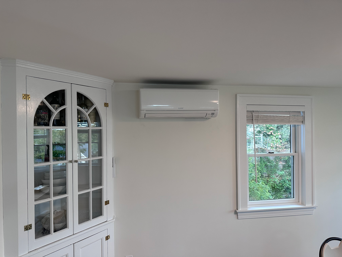 A living room with a refrigerator and a window.