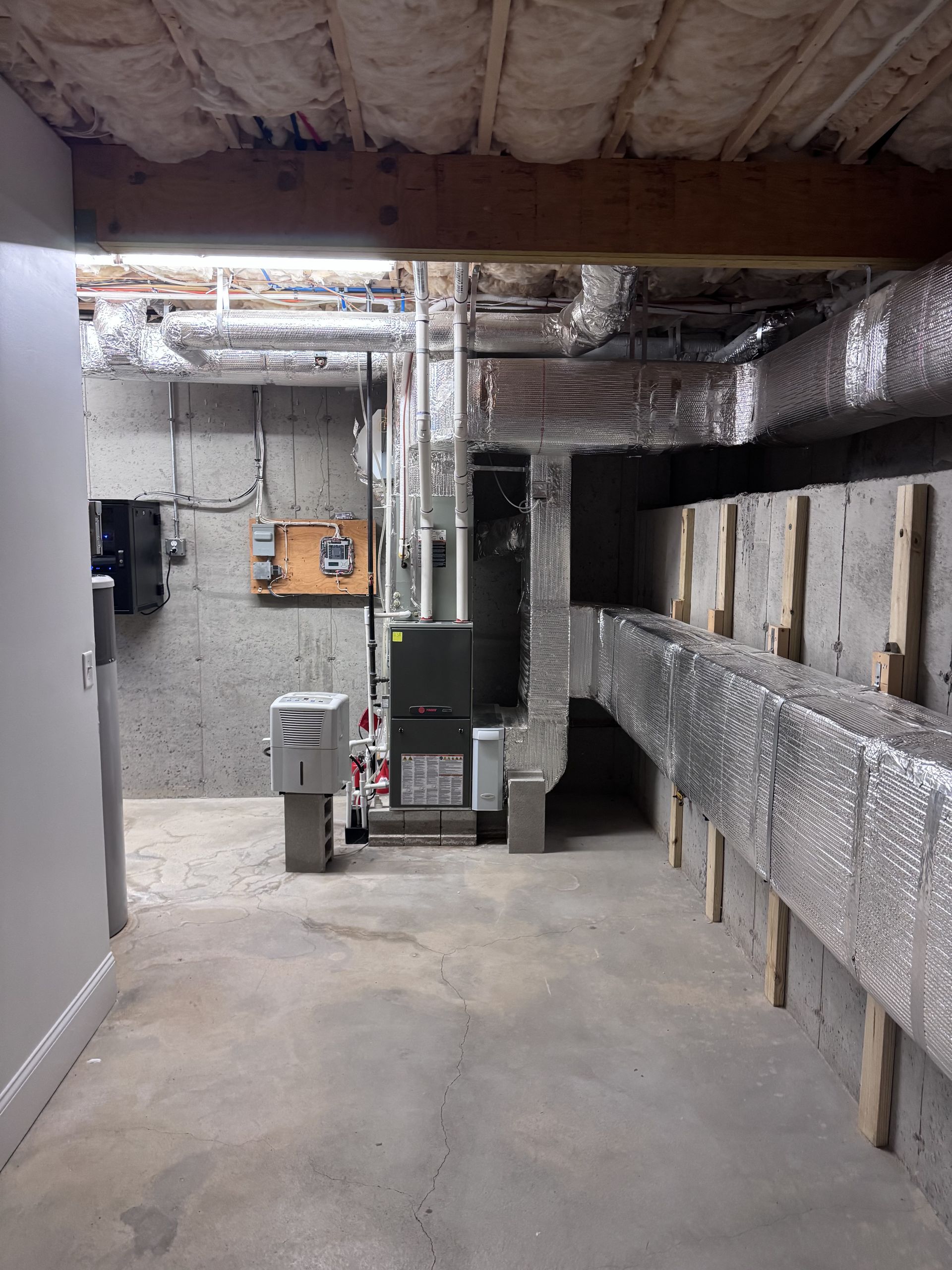 An empty basement with a furnace and air ducts