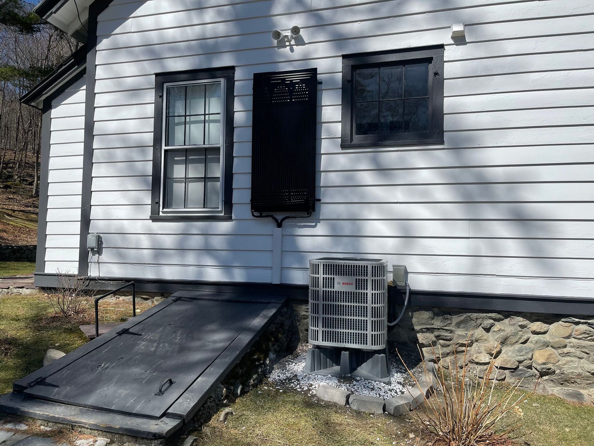 A white house with a black door and a wheelchair ramp.