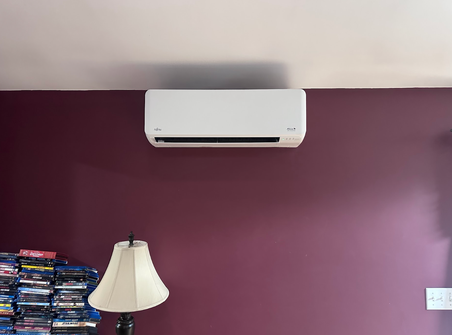 A man is installing an air conditioner on a wall.