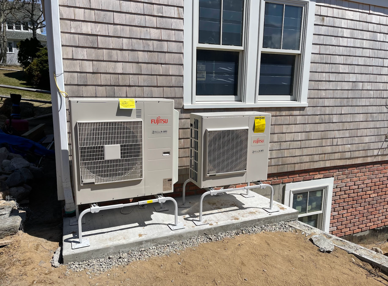 Two air conditioners are sitting on the side of a house.