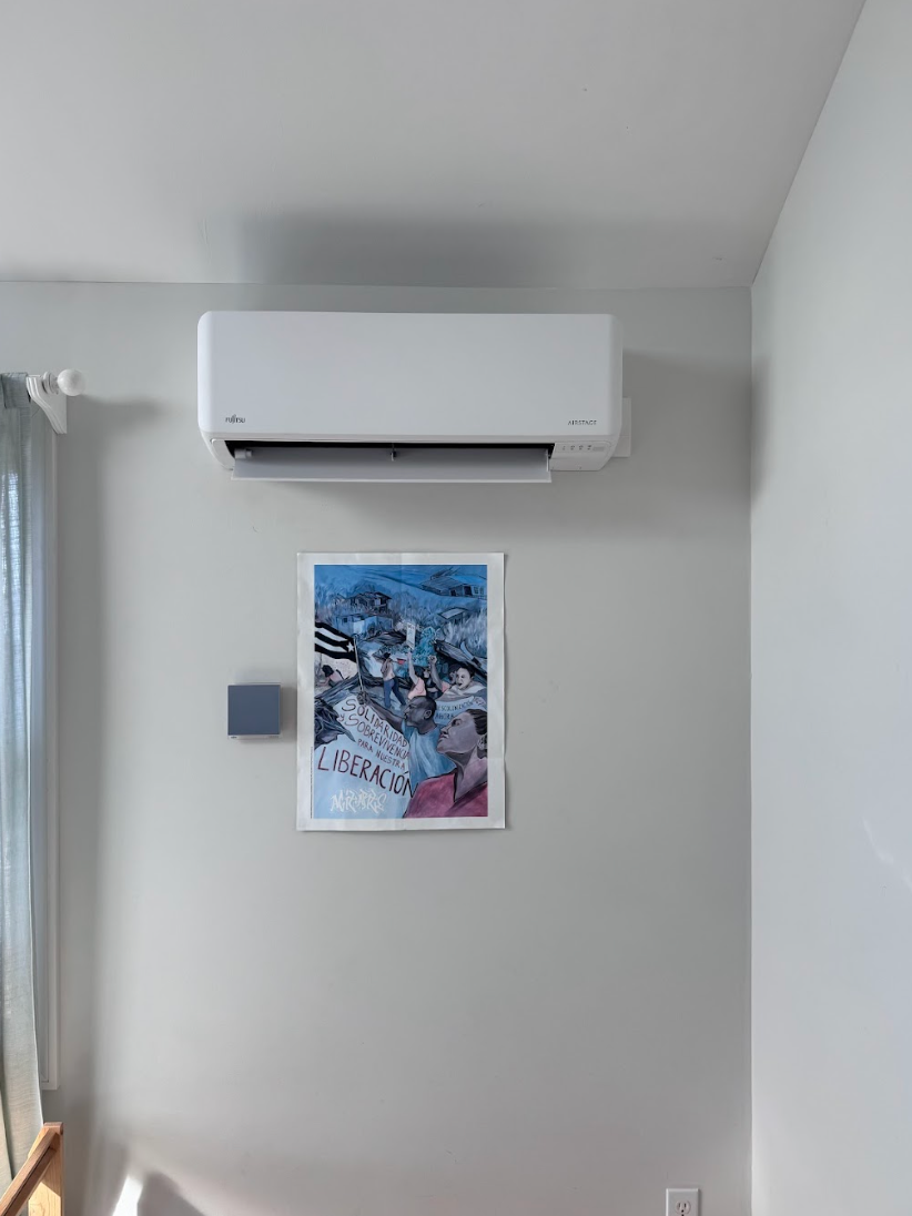 There is a picture on the wall above the air conditioner.