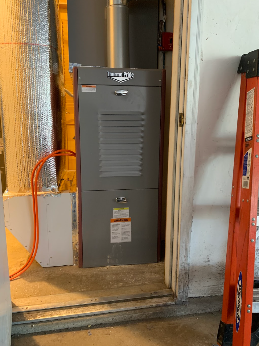 An air conditioner is sitting in a garage next to a ladder.