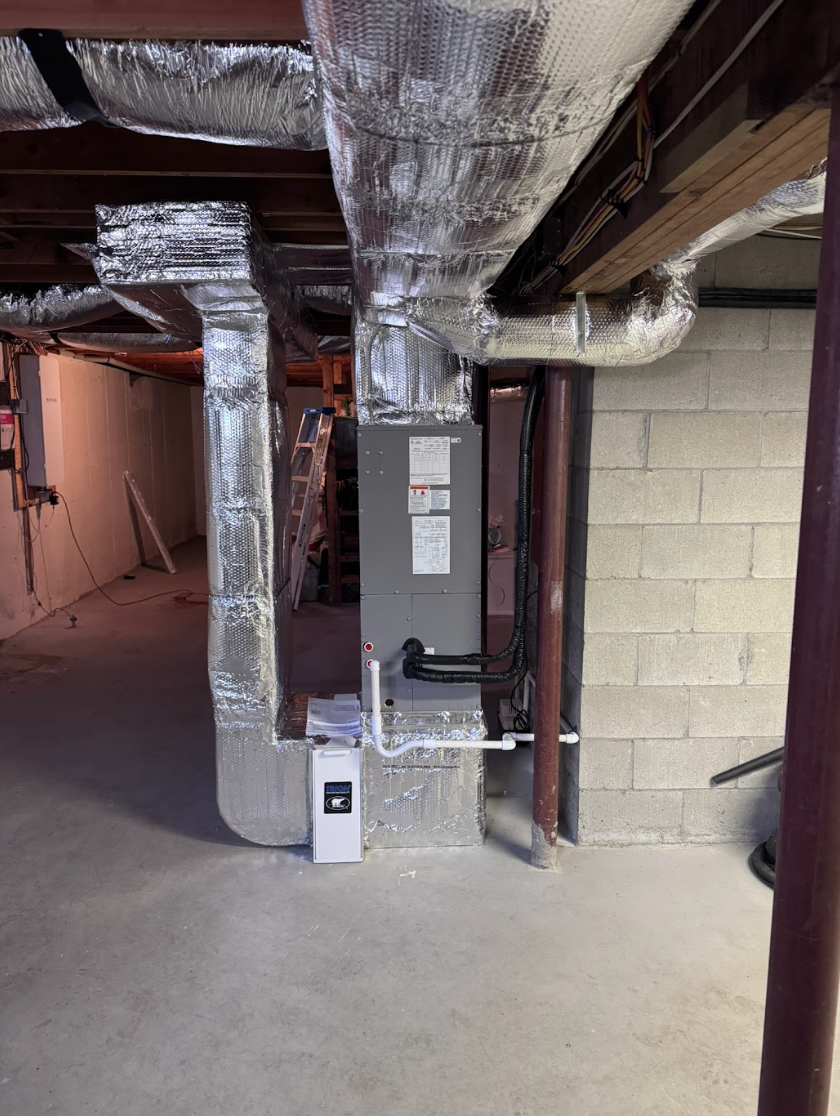 An air conditioner is sitting in a garage next to a ladder.