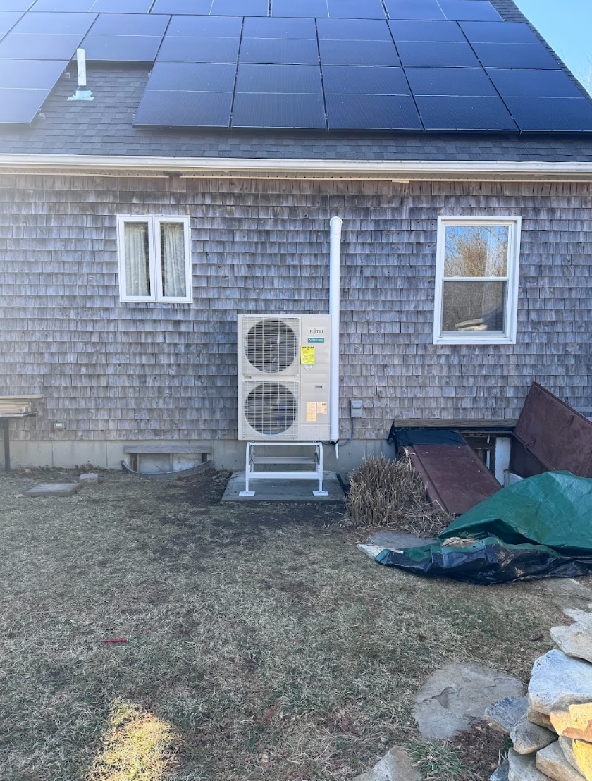 A house with a large air conditioner on the side of it and solar panels on the roof.