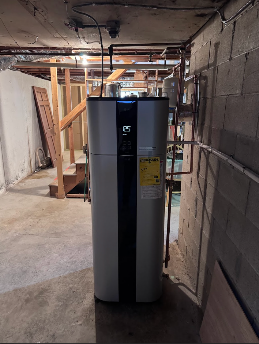 A large white water heater is sitting in a dark basement.