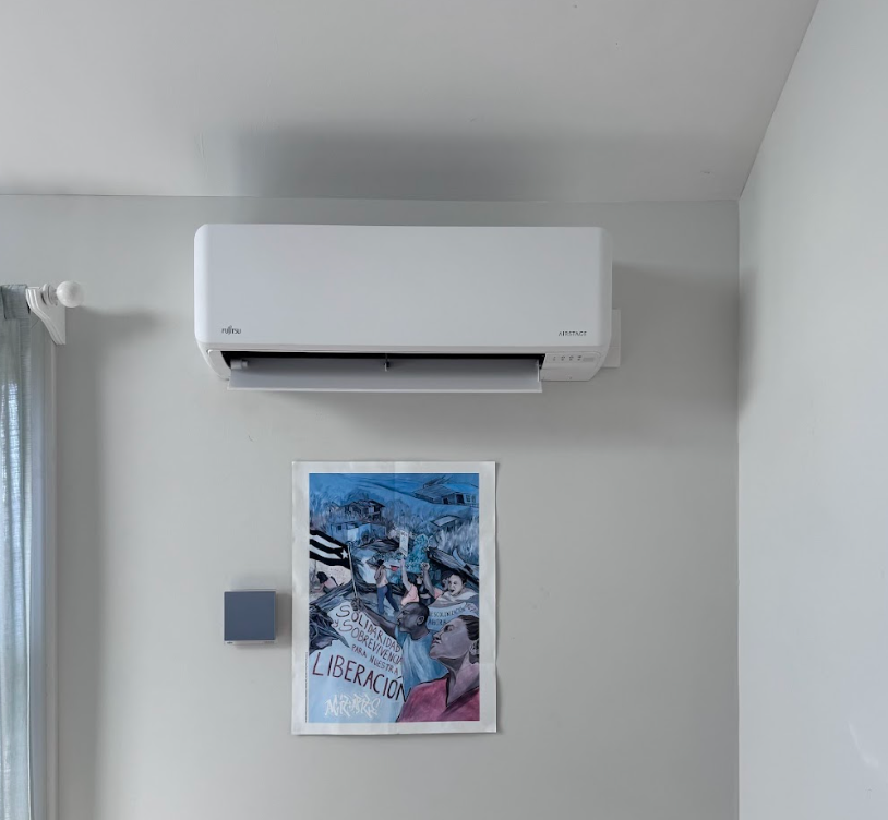 A white air conditioner is hanging from the ceiling in a room.