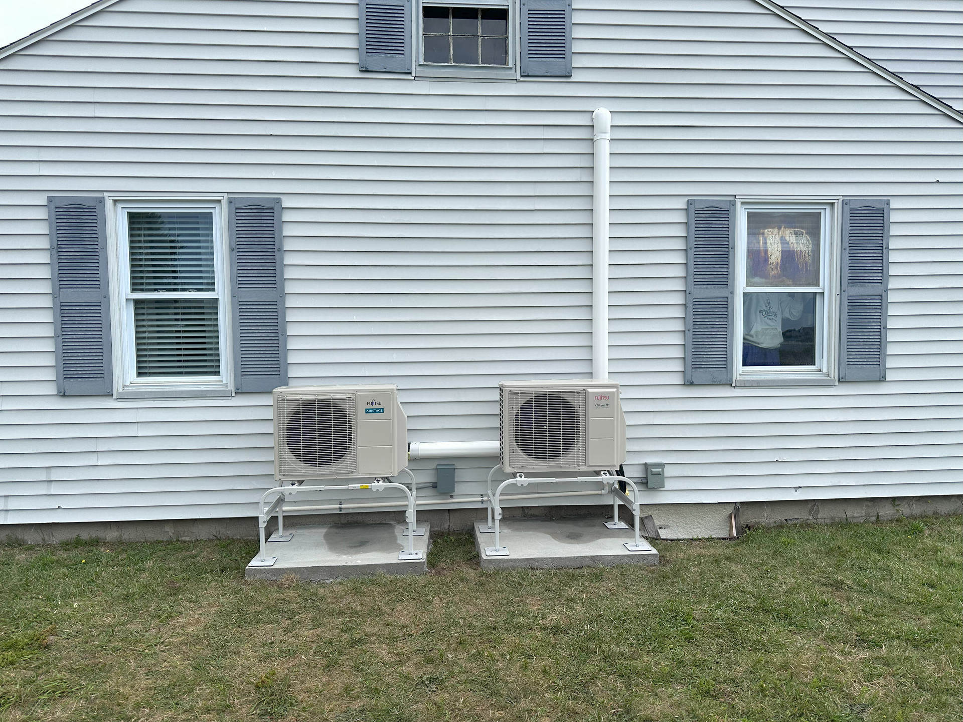 There are two air conditioners on the side of a house.