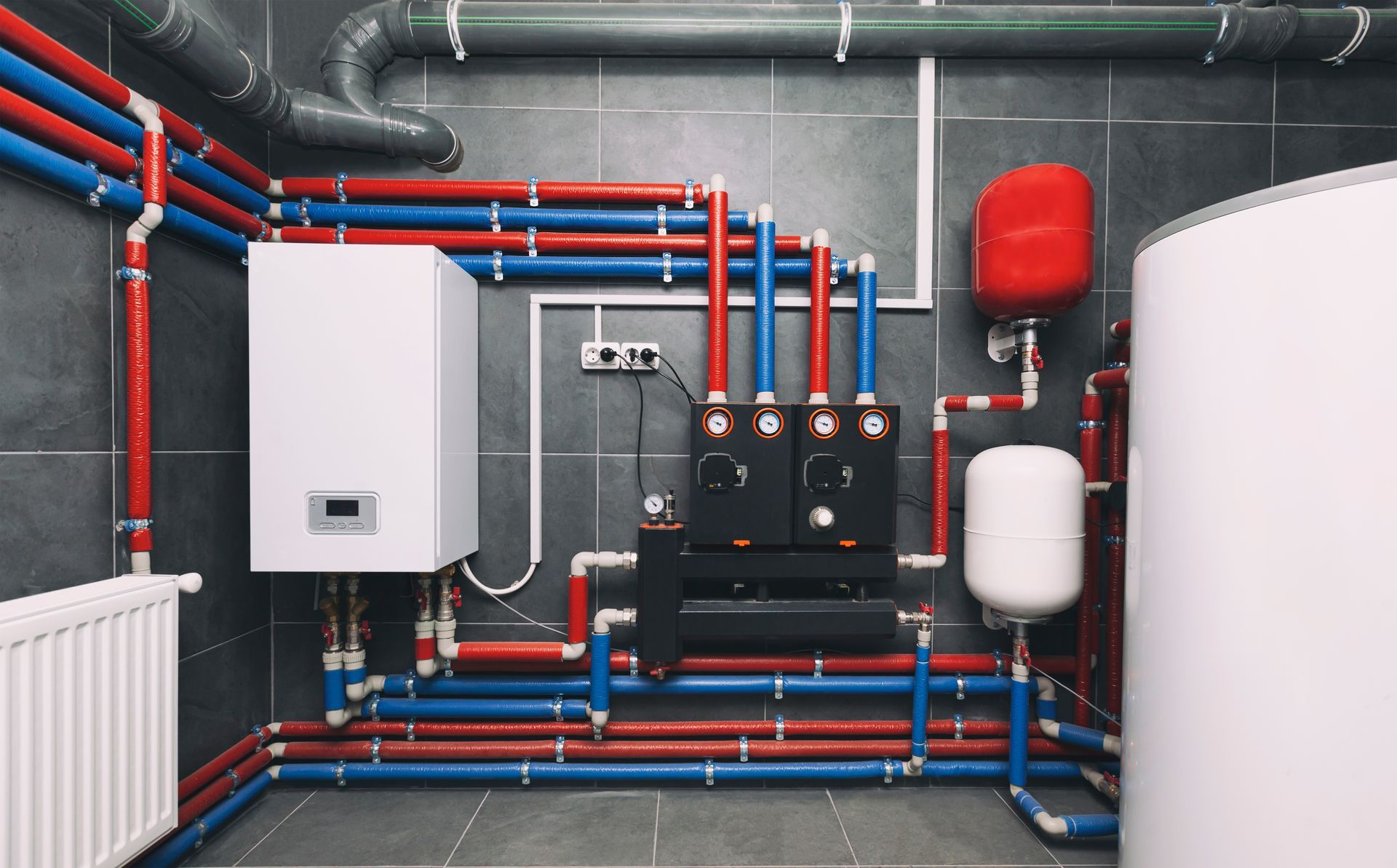 A room with a lot of pipes and a boiler on the wall.