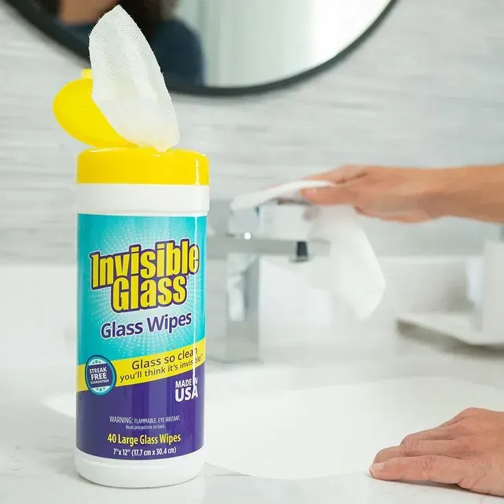 A person is using invisible glass glass wipes in a bathroom
