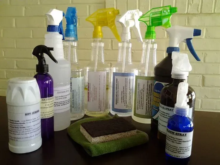 Bottles of spray cleaners and a sponge on a table