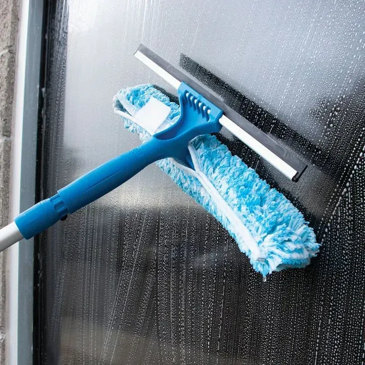 A blue mop is being used to clean a window