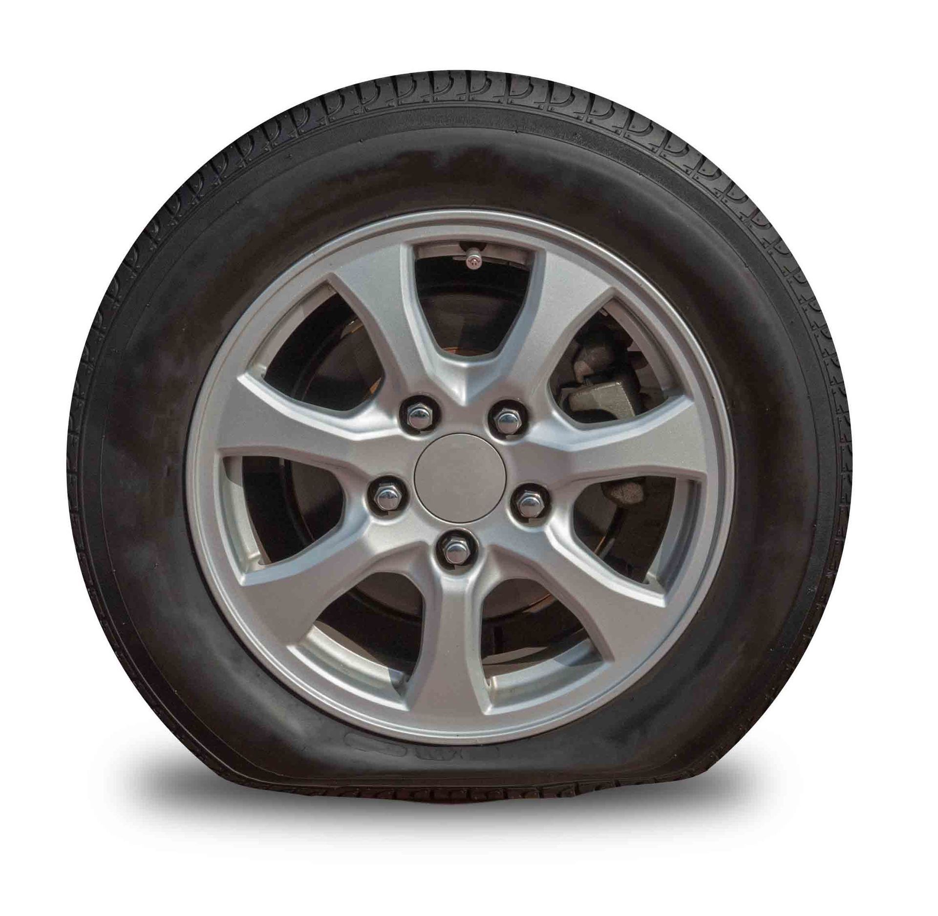 Flat car tire on a silver rim, resting on the ground.