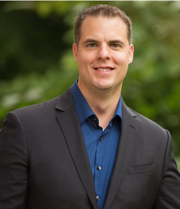 Keith Goeringer in a suit and blue shirt is smiling for the camera .