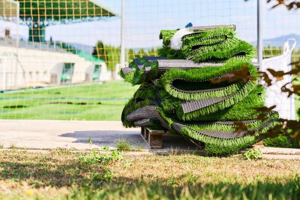 A pile of artificial grass is sitting on top of a wooden pallet on a soccer field.