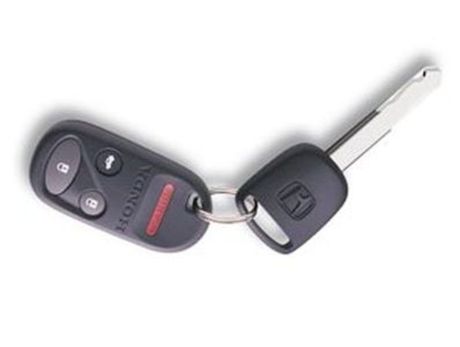 Hand holding a car key fob aimed at an open trunk in a parking lot