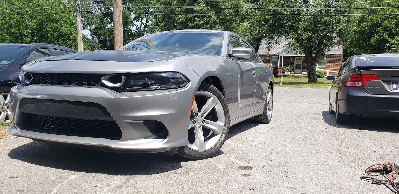 Silver sports car parked outdoors beside a black sedan on a sunny street