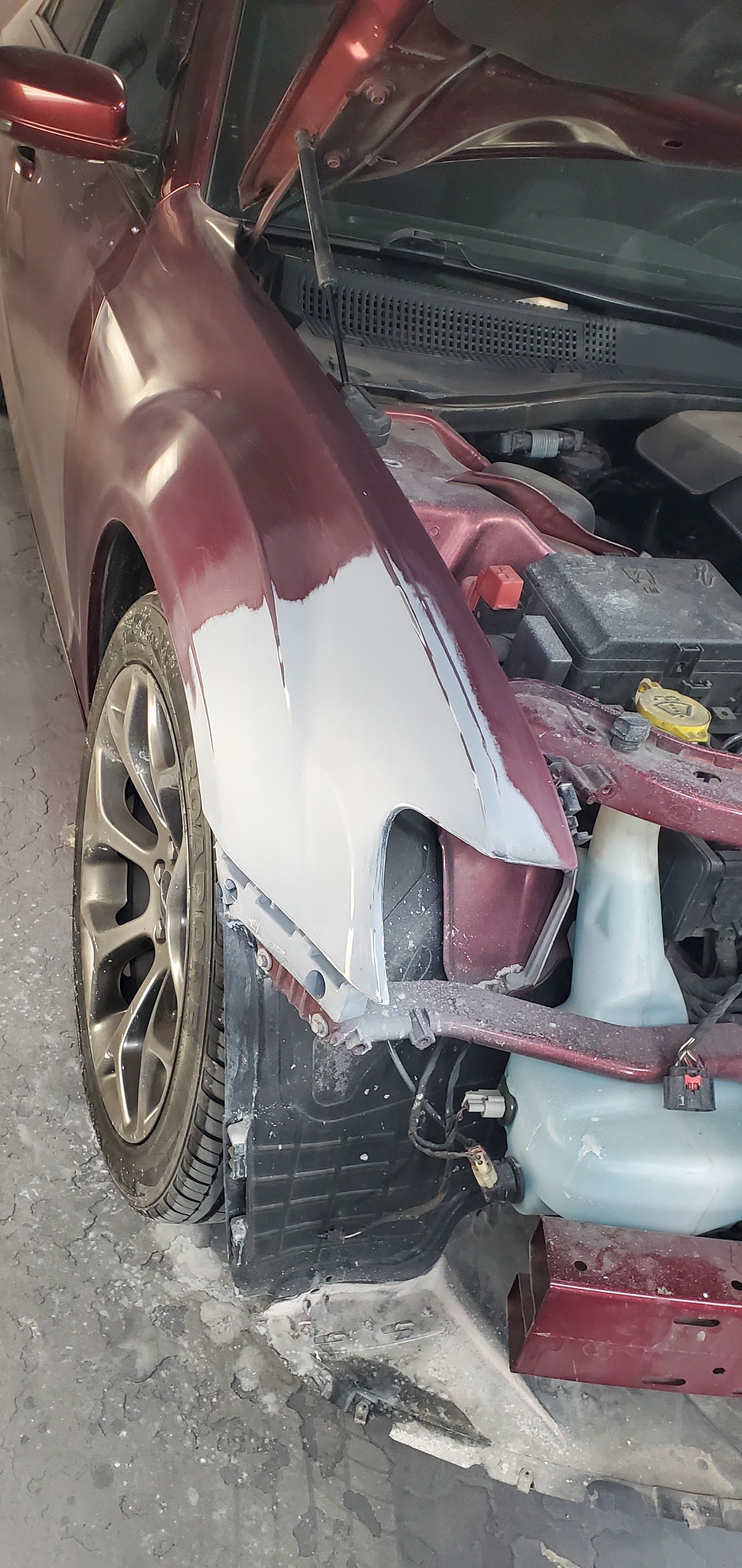 Damaged red car with a crumpled front end and torn bumper after a collision