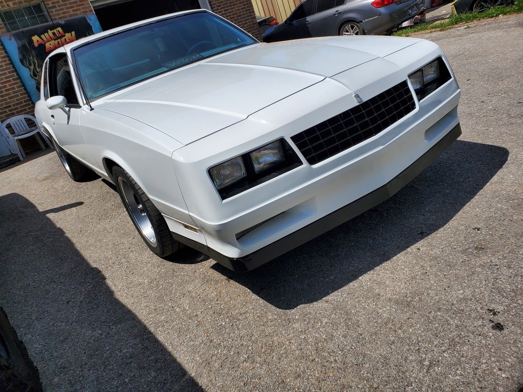 White classic muscle car parked on pavement, front three-quarter view outdoors