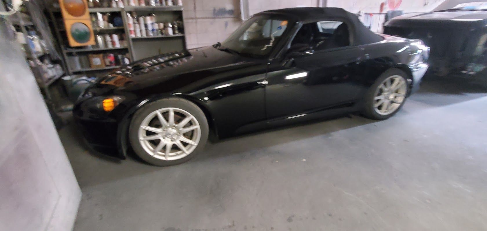 Black sports car parked in a garage, side view with silver rims
