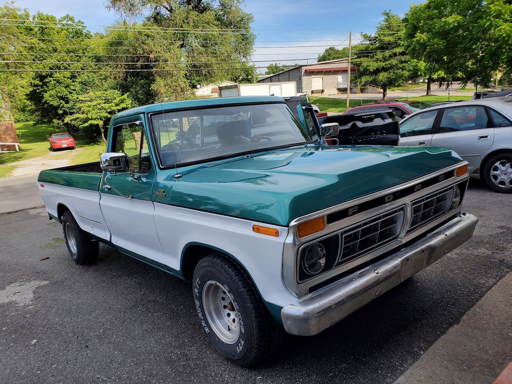 Green and white vintage pickup truck parked on a street beside other cars