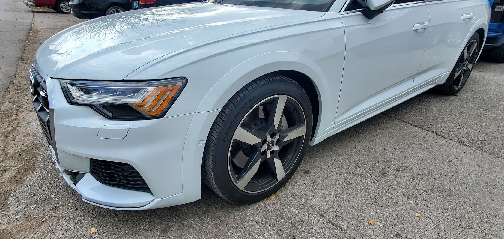 White sports sedan parked on a paved lot, front-left view with dark alloy wheels.