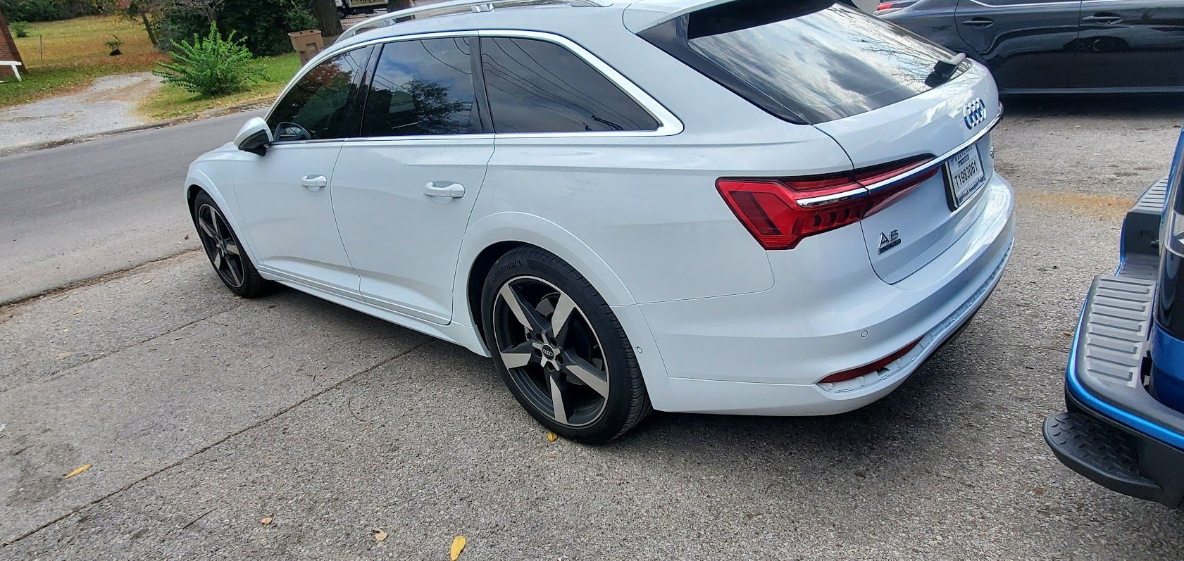 White Audi wagon parked on a gravel lot, rear three-quarter view, with tinted windows and black wheels