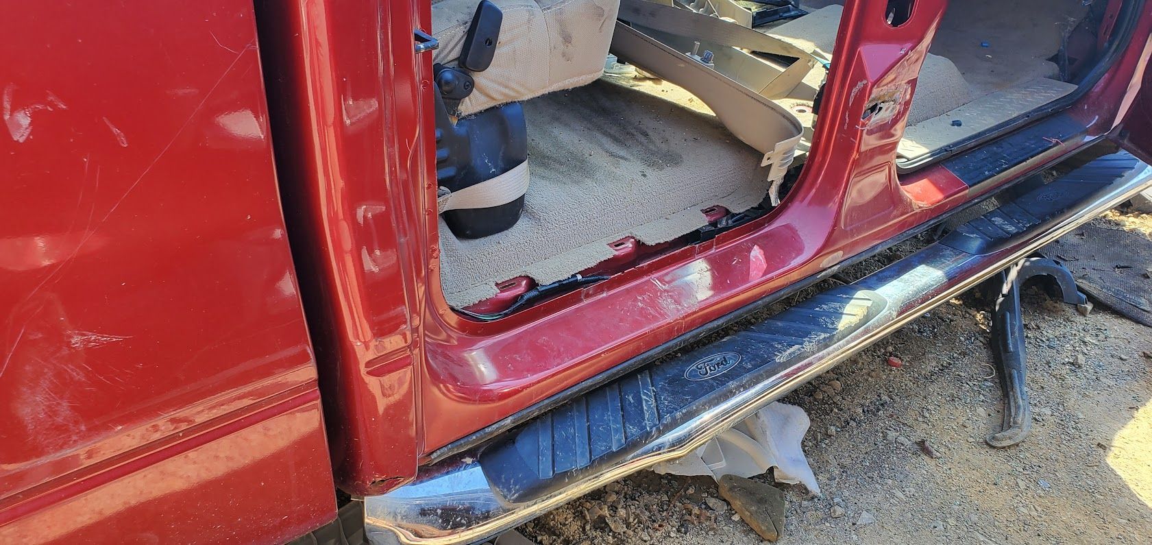 Damaged red car with missing door and crushed side panel
