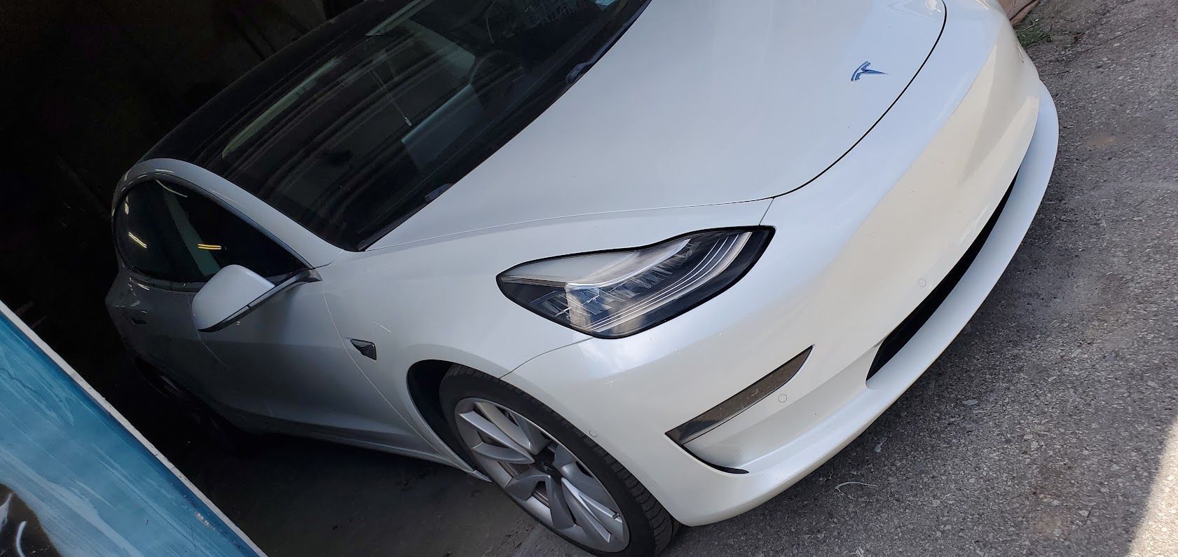 White Tesla parked at a curb, viewed from above at an angle