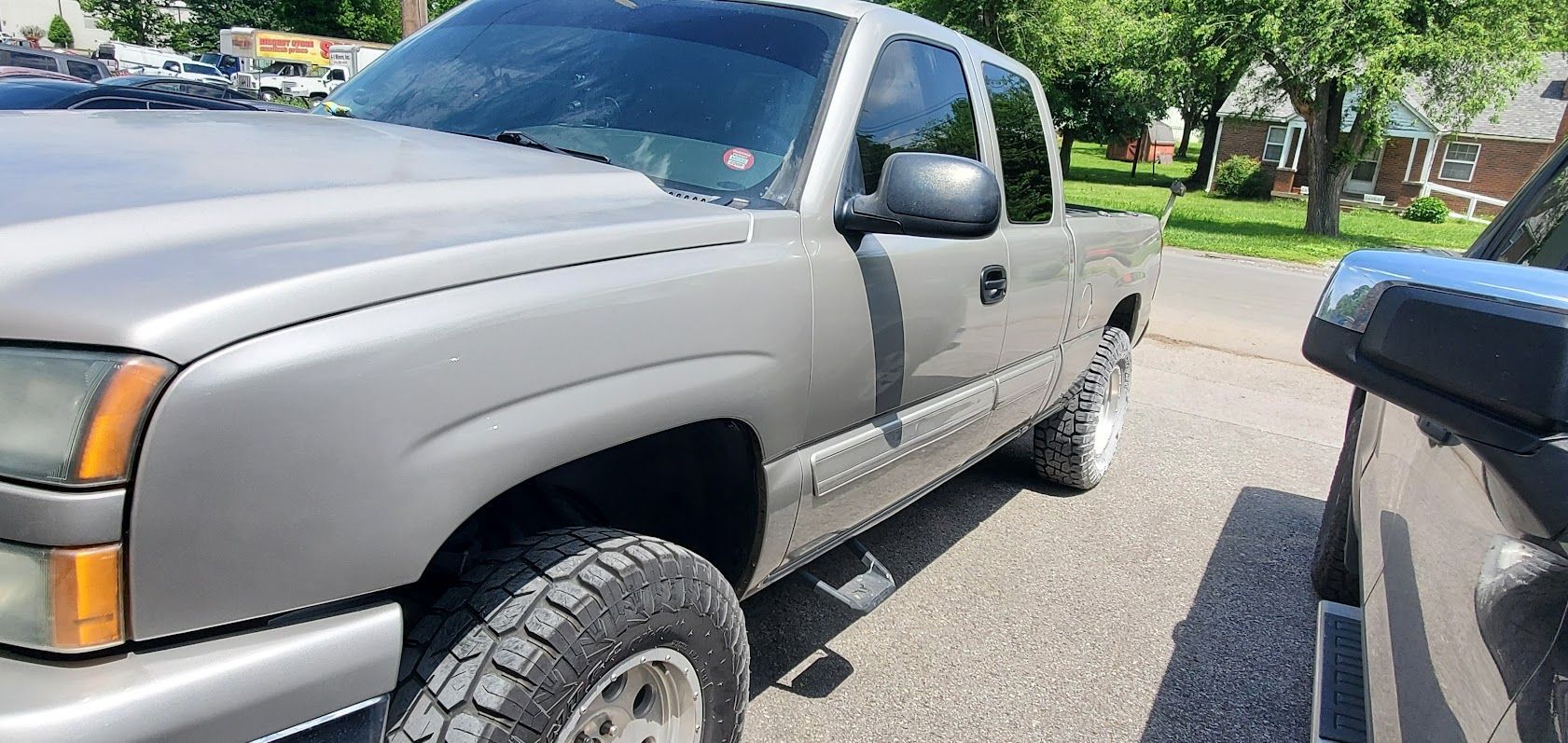 Gray pickup truck parked beside a black vehicle on a sunny street.