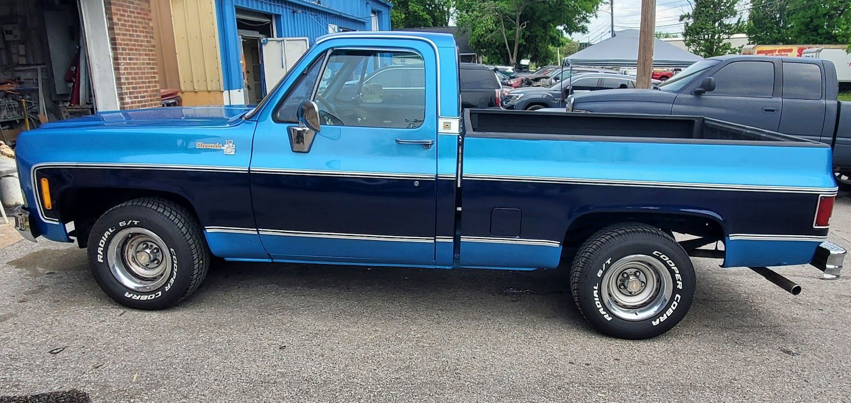 Blue and black vintage pickup truck parked on a gravel lot.