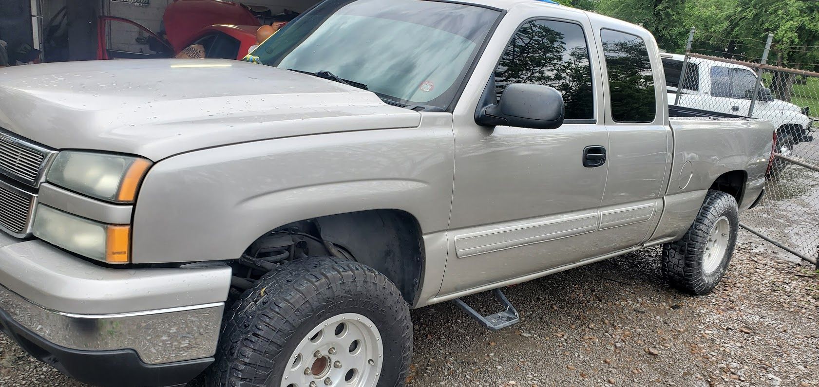 Silver pickup truck parked on gravel, side view with off-road tires and crew cab