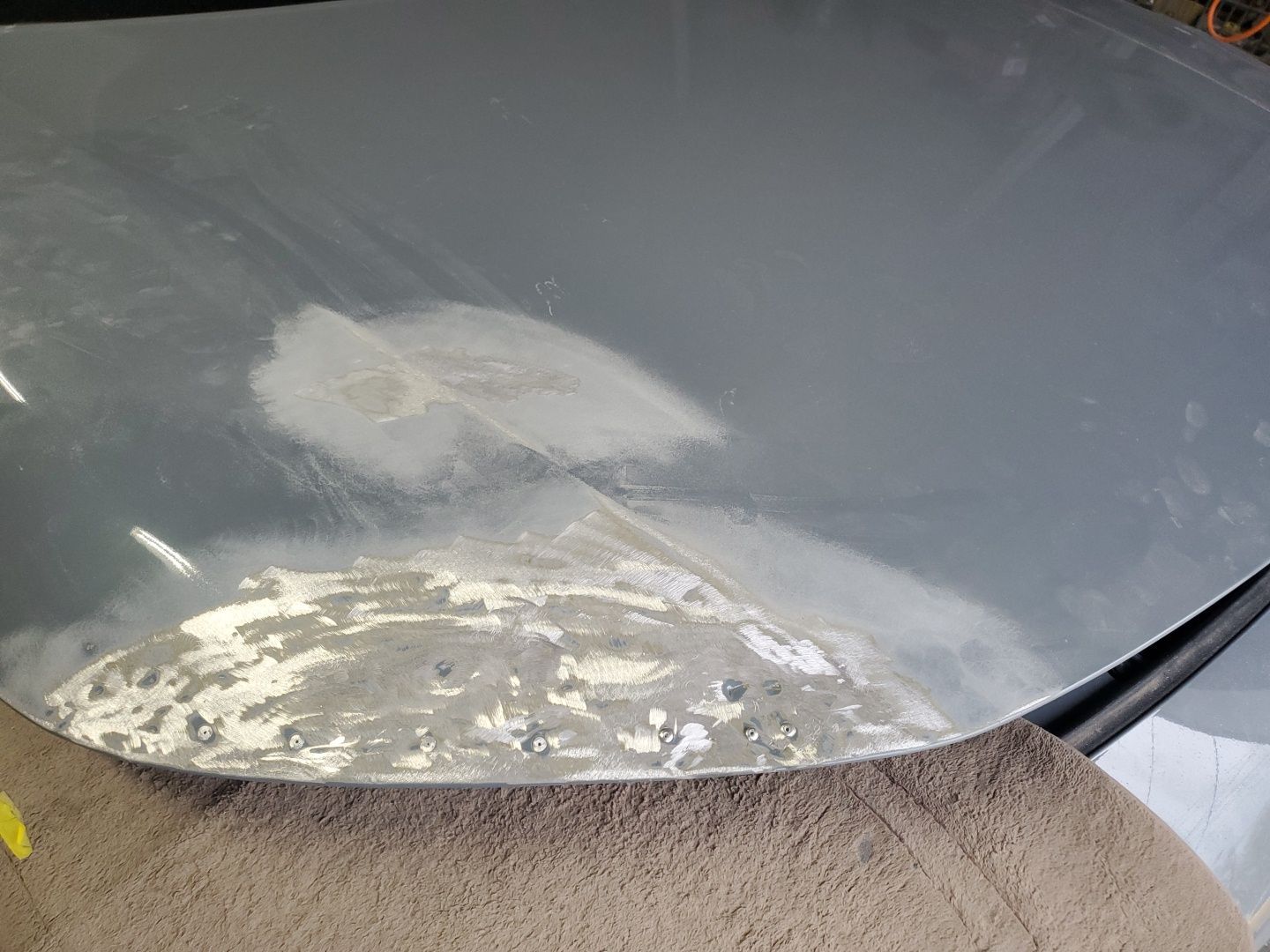 Close-up of a gray metal surface with a large worn patch and chipped white paint near the edge