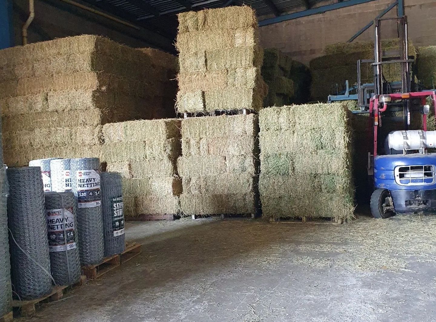 Hay Bales Stacked And Heavy Netting — Kempsey Produce & Saddlery in Kempsey, NSW