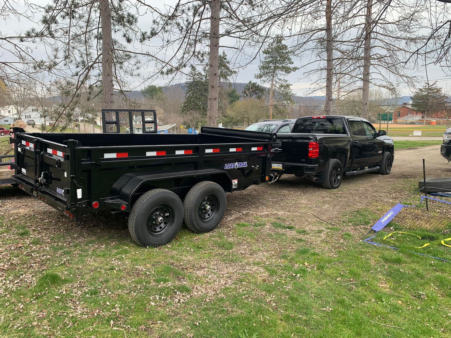 A black truck is towing a black dump trailer.