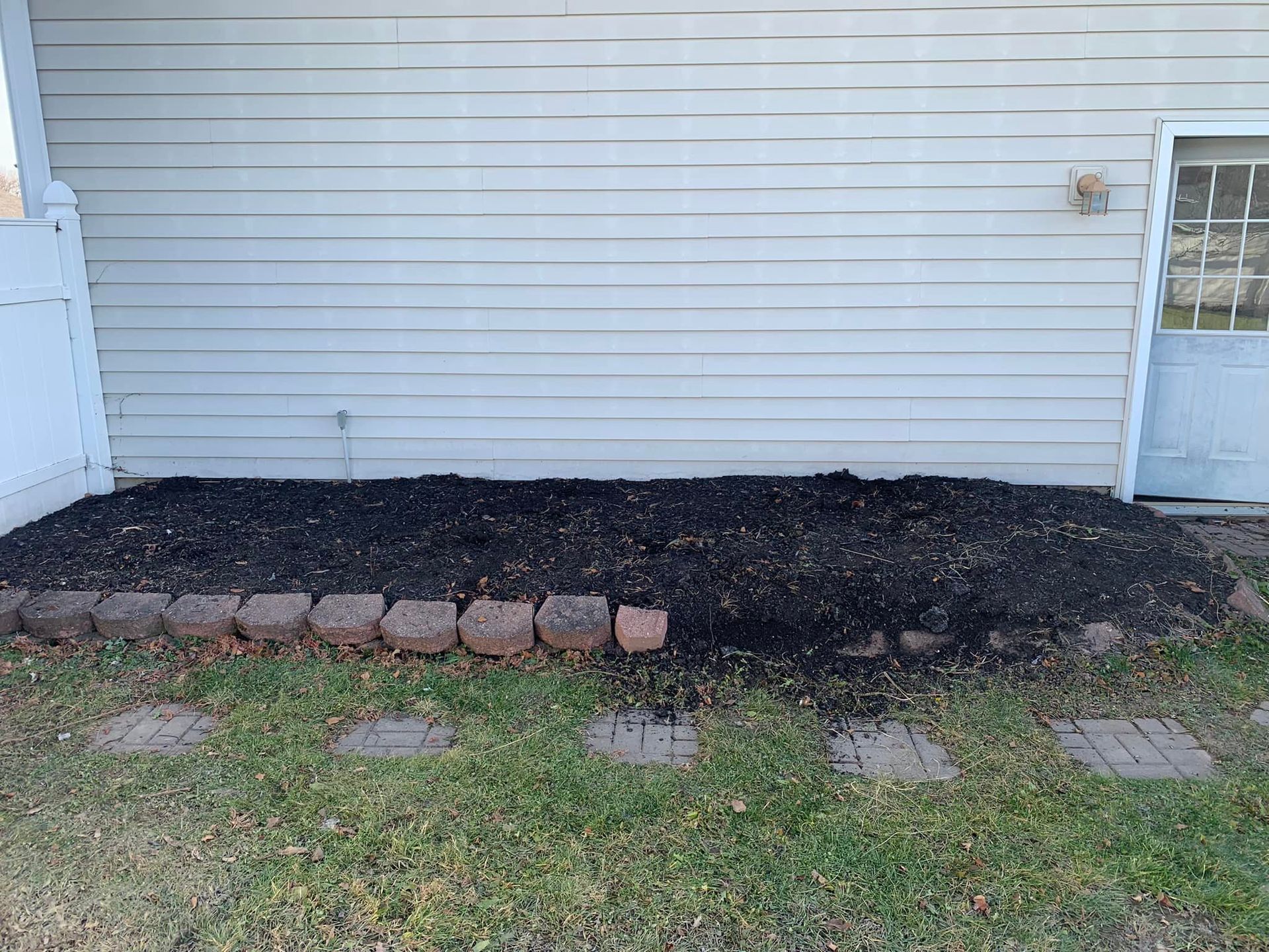 There is a pile of mulch in front of a house.