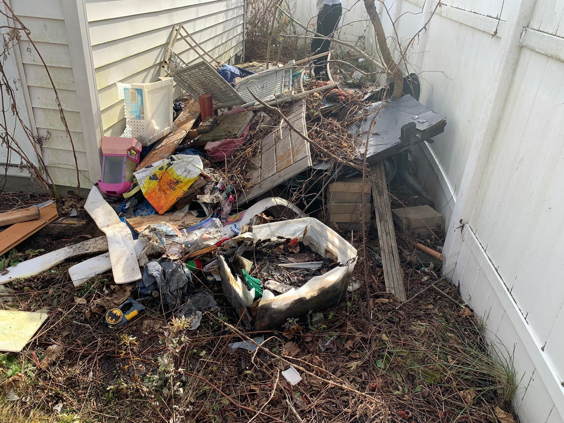 A pile of trash is sitting in front of a white fence.