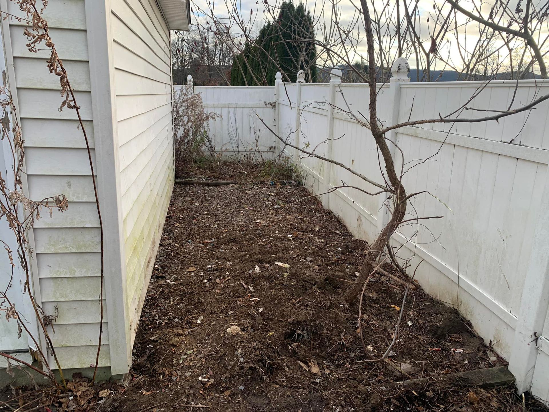 A backyard with a white fence and a white house