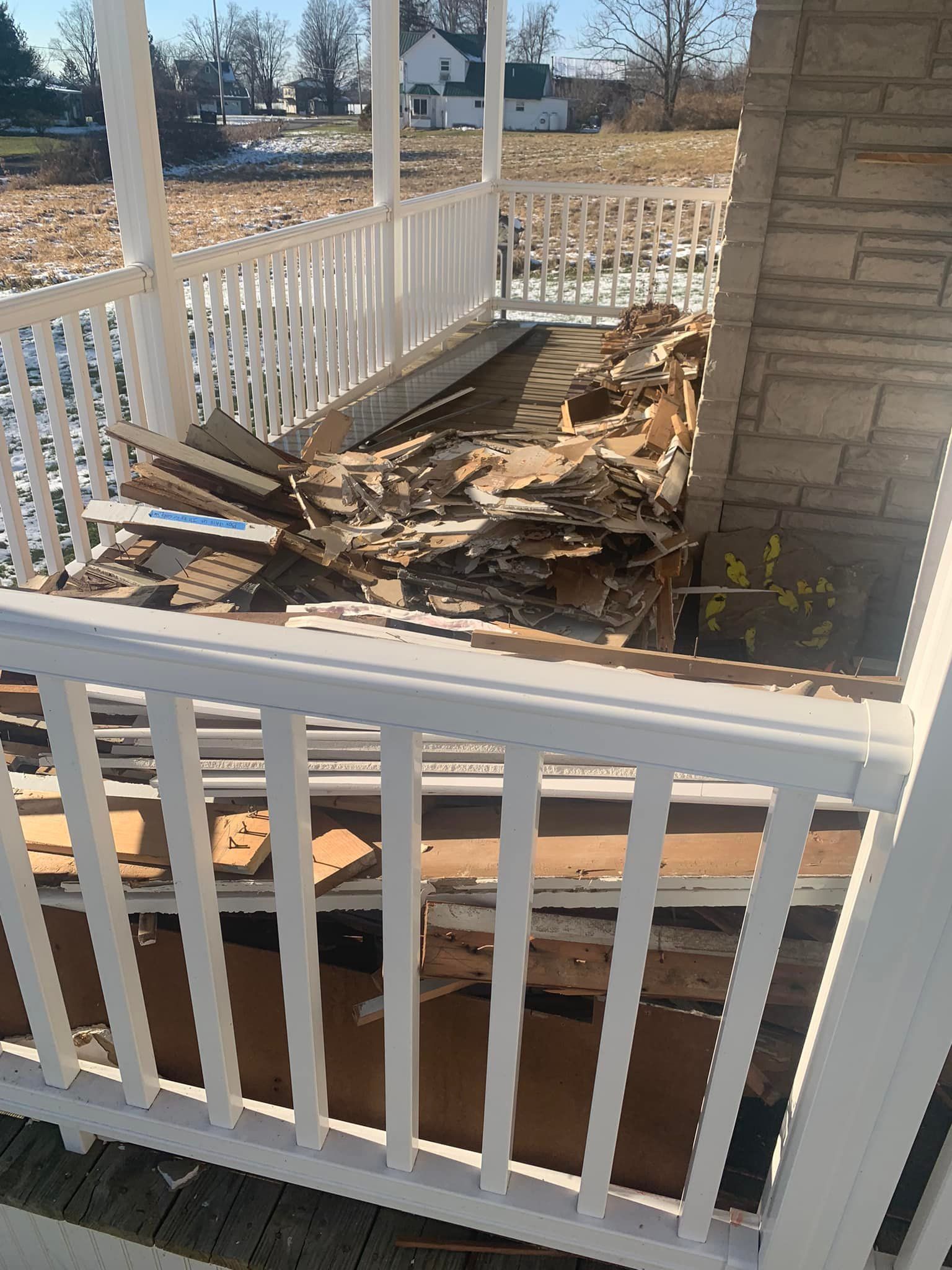 A porch with a white railing is being demolished.
