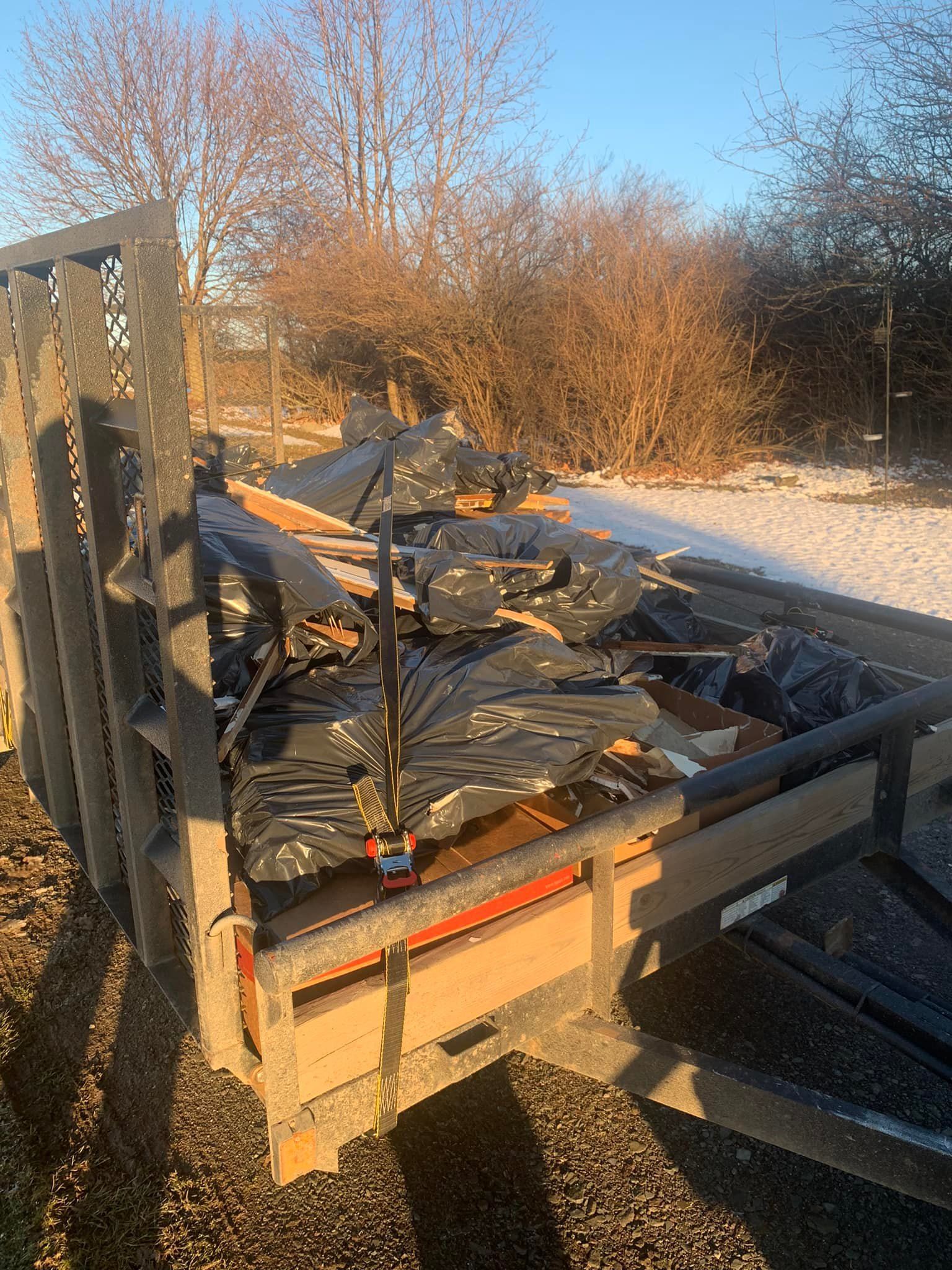 A trailer filled with a lot of junk is parked on the side of the road.
