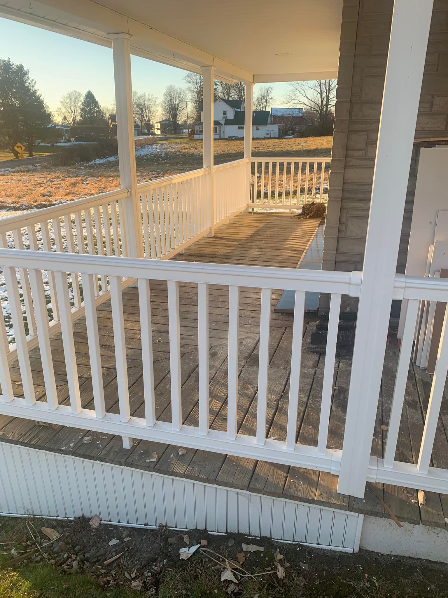 A porch with a white railing and a wooden floor.